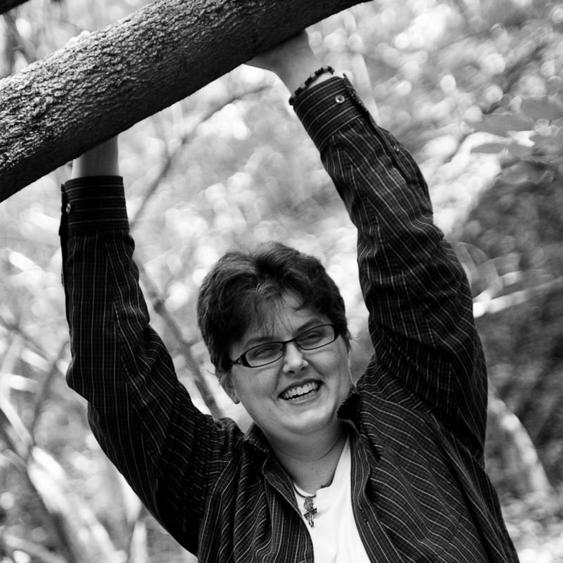 A picture of me outside with my hands resting on a tree branch over my head