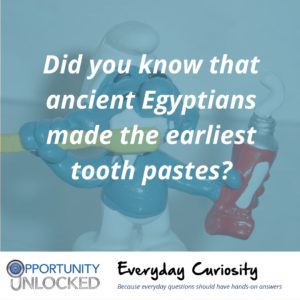 White text overlaid on a picture of a smurf with a toothbrush and a tube of toothpaste reads "Did you know that ancient Egyptians made the earliest tooth pastes?" The banner at the bottom includes the full Opportunity Unlocked logo and "Everyday Curiosity: Because everyday questions should have hands-on answers"