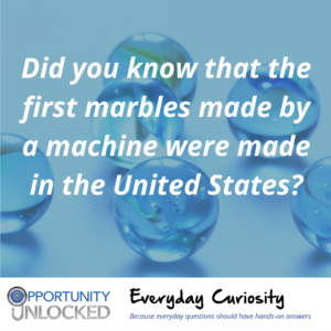 White text overlaid on a close-up picture of several marbles reads "Did you know that the first marbles made by a machine were made in the United States?" The banner at the bottom includes the full Opportunity Unlocked logo and "Everyday Curiosity: Because everyday questions should have hands-on answers"